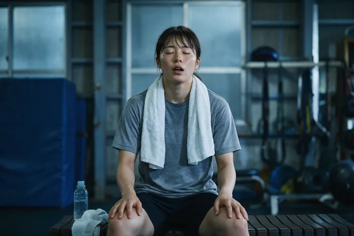 トレーニング後、ベンチで呼吸を整える女性